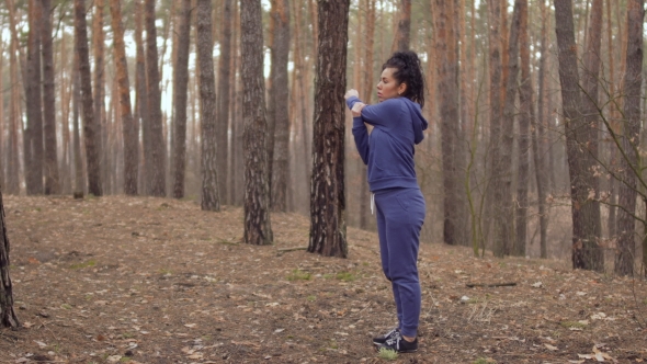 Young Woman in Sportswear Makes a Sport Exercise for Hands in the Forest