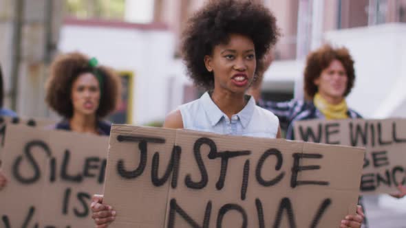 Diverse group of men and women holding placards shouting during protest