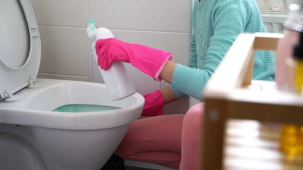 Woman with a Rubber Glove Cleans a Toilet Bowl