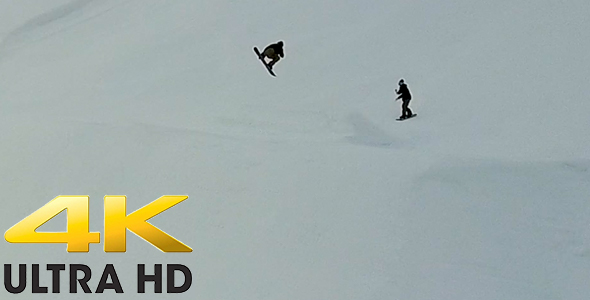 Snow Boarders Taking a Jump on a Ski Field