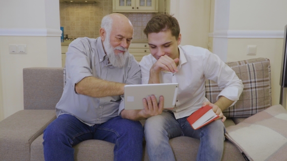Modern Grandfather Shows Video To His Grandson in the Internet on Digital Tablet
