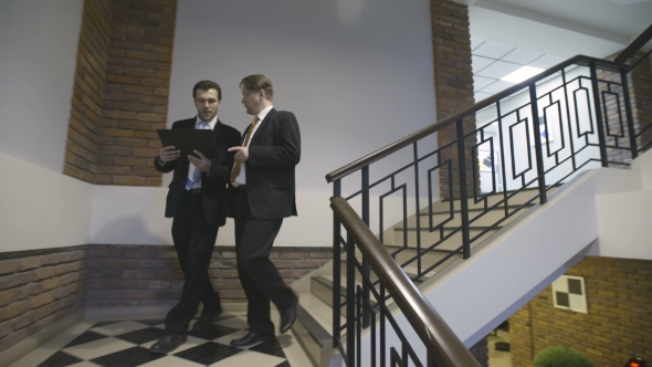 Businessmen Go Down the Stairs and Discuss Project