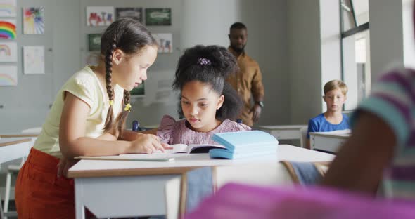 Video of diverse girls at desk doing lessons together in classroom