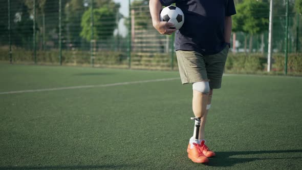 Unrecognizable Man with Artificial Limbs and Soccer Ball Walking in Slow Motion on Sunny Sports