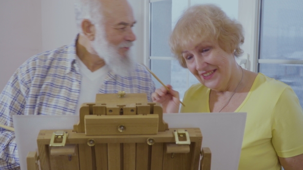 Senior Man Has Fun with His Wife Drawing the Picture on Easel