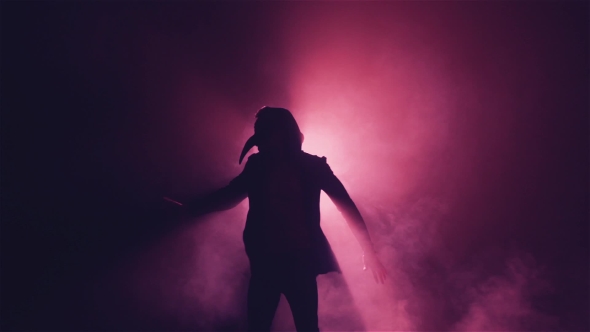 Silhouette of a Man in Mask Dance in Smoke