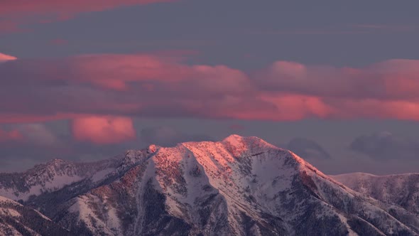 Time lapse of colorful clouds over snow capped mountain during sunset