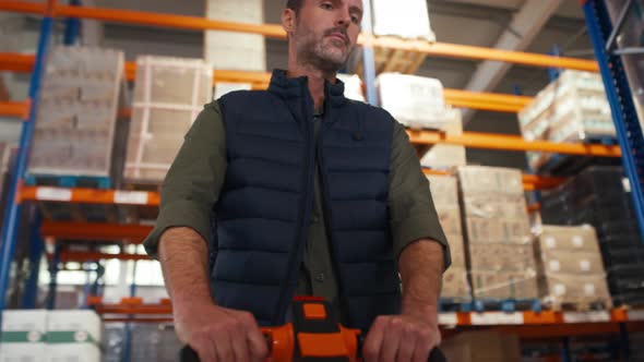 Adult caucasian man working pulling forklift in a warehouse. Shot with RED helium camera in 8K.