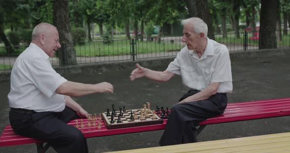 Two Nice Seniors Men Playing the Chess Game Using Clock and Having a Talk