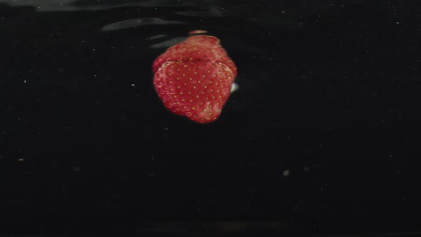 Fresh Strawberries Splashing Falling in Water on Slow Motion with Reflections