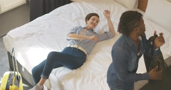 Top View of Carefree Beautiful Caucasian Woman Falling Back on White Bed in Hotel Room As Young