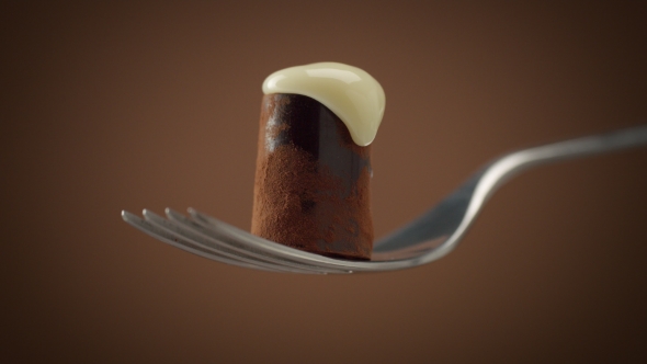 One Chocolate Candy on Fork Covered By White Cream, Slowly Falling Down