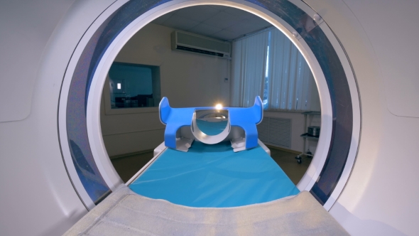 An Empty Patients Cot Moves Inside a CT Scanner alt