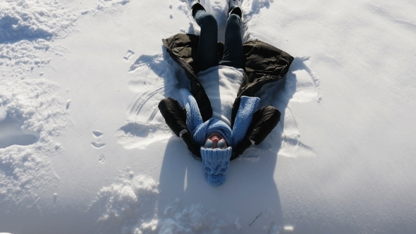 Girl Falls and Lies on Snow in Blue Hat