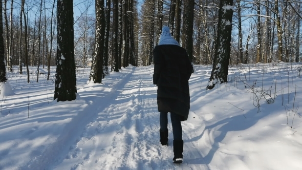 Woman in a Jacket and a Blue Hat and with a Scarf Goes Along the Alley