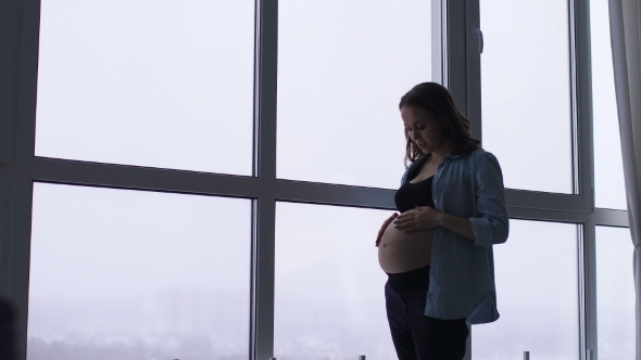 The Morning of a Happy Smiling Pregnant Woman in a Chic Apartment with Panoramic Windows A Woman Is