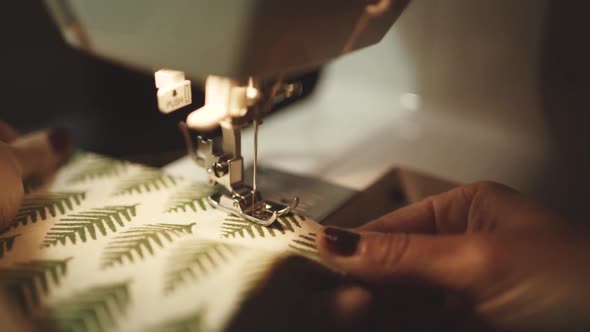 tailor sewing on machine near brick wall in atelier