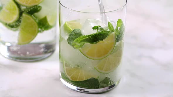 Pour lime and mint water into glass.