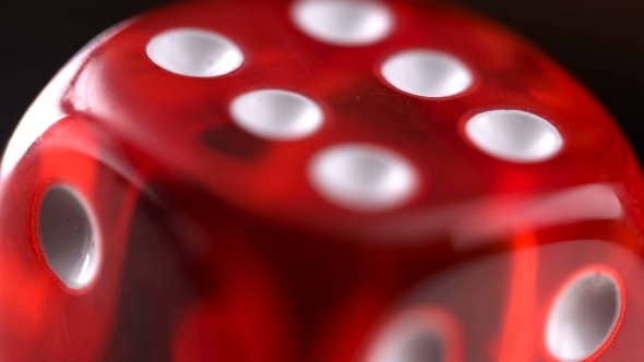 Rotating Red Dice Around Its Axis, on a Black Background alt