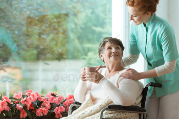 chair of a sick elder woman with cup of tea