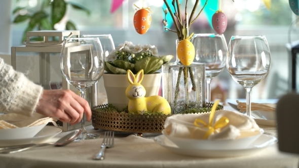 Young Woman Setting Easter Festive Table with Bunny and Eggs Decoration