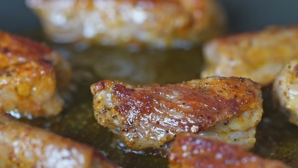 Pieces of Meat with Spices Are Fried in a Pan  View