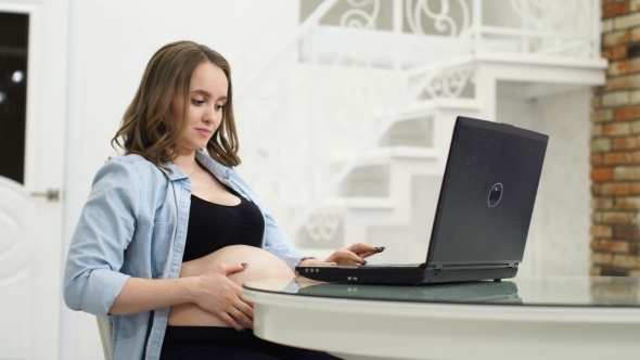 A Pregnant Woman Is Engaged in Business During Maternity Leave. Sitting at the Computer