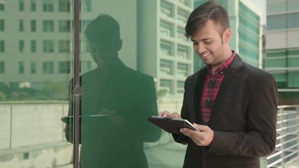 Static Shot of Busy Indian Young Man Working with Tablet