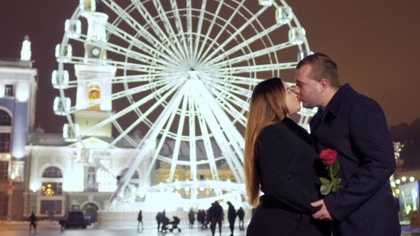 In Love Couple Kisses at Ferris Wheel Background
