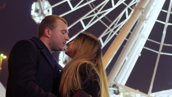 Beautiful in Love Couple Kisses at Ferris Wheel Background