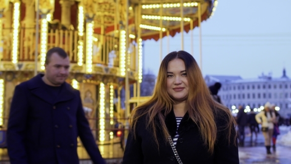 Handsome Man Meets with His Wife Near the Carousel in Amusement Park
