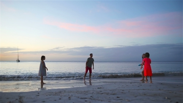 Happy Family of Four Playing Together on the Beach