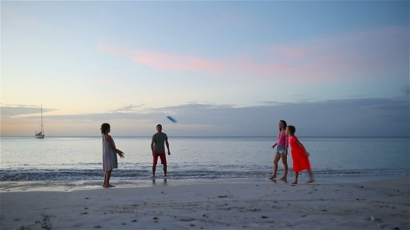 Happy Family Playing with Flying Disk at Beach at Sunset