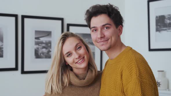 Happy Young Couple Hugging Looking at Camera Standing at Home Portrait