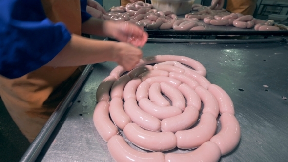 A Butcher Is Working with a Link of Sausages Bare Handed