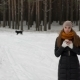 Pretty Girl in the Winter Woods Taking a Selfie. Nearby Runs a Black Dog - VideoHive Item for Sale