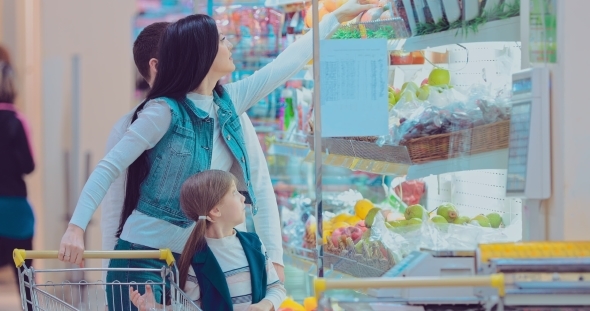 Mother, Father and Children Picking Out Fruit in Supermarket