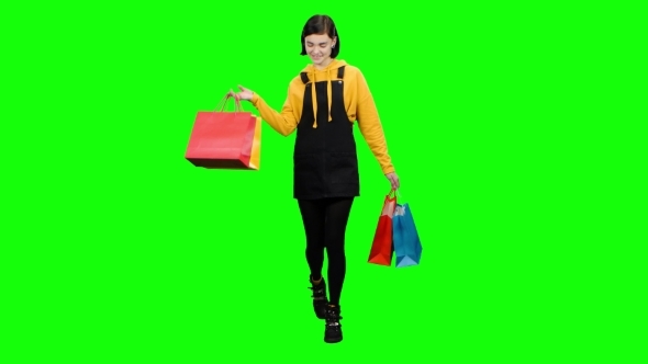 Teen Is Walking Along the Street with Packages in Her Hands. Green Screen