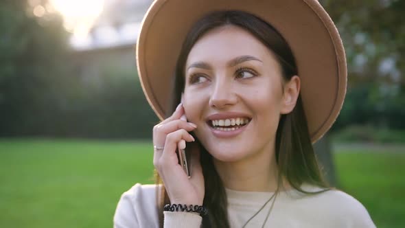 Cheerful Lovely Good-Looking Lady in Stylish Hat Talking on Smartphone Outdoors