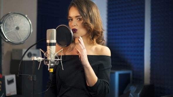 Beautiful Woman Singing Into a Large Microphone. Professional Recording Studio.