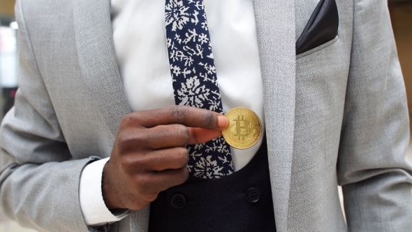 Black Man Wearing Business Suit Holding Half Gold Bitcoin From Pocket.