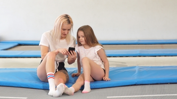 Mother And Her Daughter Sitting on Trampoline in Fitness Park