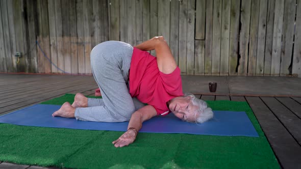 Senior mature gray haired woman does a yoga pose.