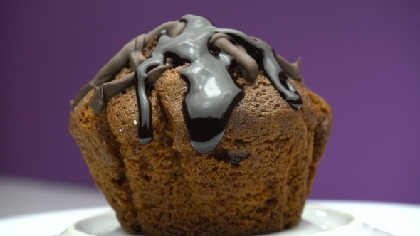 Cupcake Pouring Melted Chocolate Syrup on a Plate Spinning. Muffin Is Rotating.
