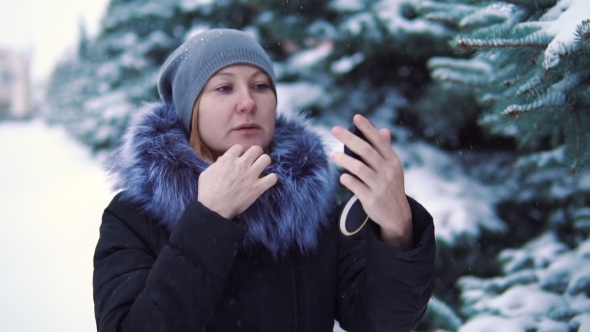 Girl Corrects Make-up in the Winter Snow-covered Park