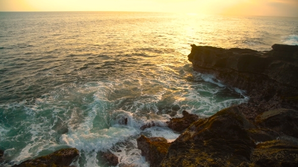 Waves Break on the Rocky Shore at Beautiful Sunset in Bali, Indonesia