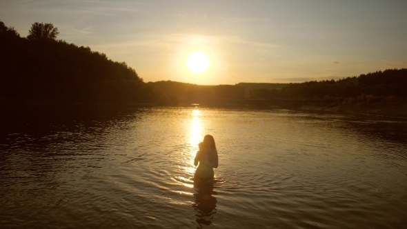 Mother and Child Bathe in River against the Sunset