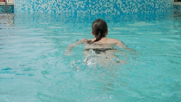 Girl Swims in the Outdoor Pool at the Hotel in a Black Swimsuit