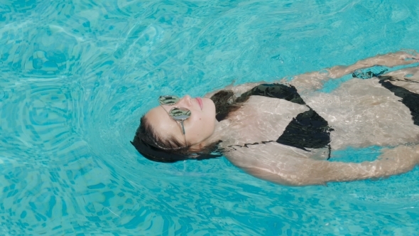 Girl Swims in the Outdoor Pool at the Hotel in a Black Swimsuit