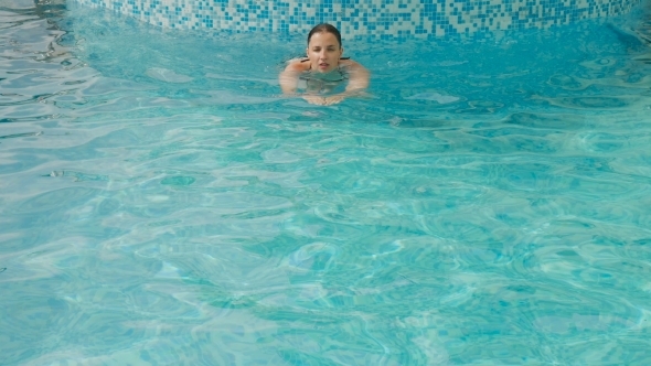 Girl Swims in the Outdoor Pool at the Hotel in a Black Swimsuit